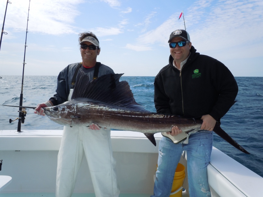 Fishing mate with client holding a marlin