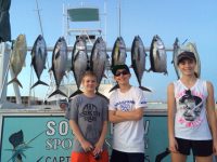 2 boys one girl with tuna fish hanging on the fish rack