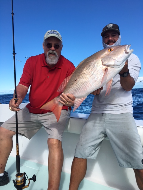 Fishing mate with client holding a freshly caught mutton snapper