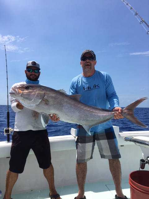 Crew and client holding a greater amberjack
