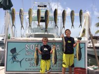 2 boys with 13 dolphin hanging on the fish rack