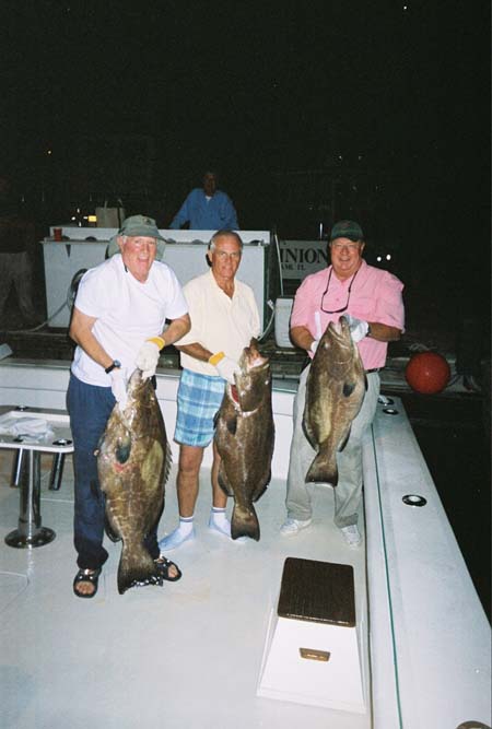 3 men holding 3 black groupers