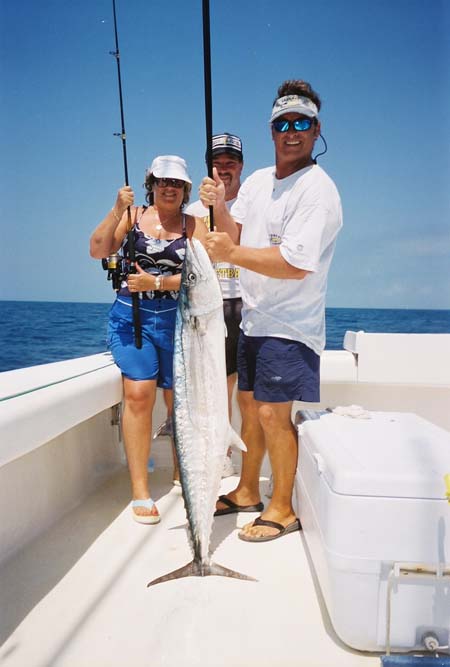 Clients and fishing crew holding a kingfish